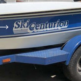 Blue and white boat with 'Ski Centurion' branding on a trailer.